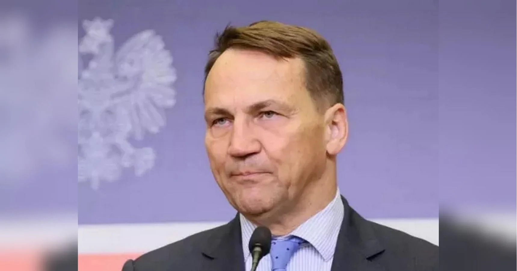 Радослав Сікорський виступає перед мікрофоном на тлі польського орла