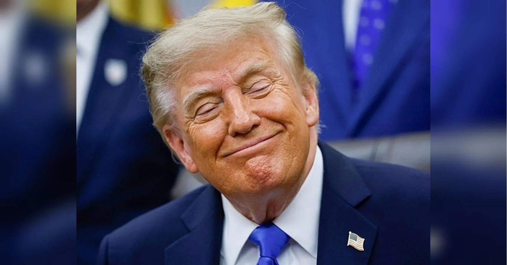 Дональд Трамп у темному костюмі посміхається на фоні республіканців
