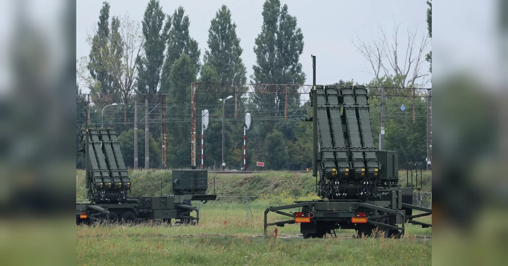Дві пускові установки Patriot на причепах біля залізниці серед трави