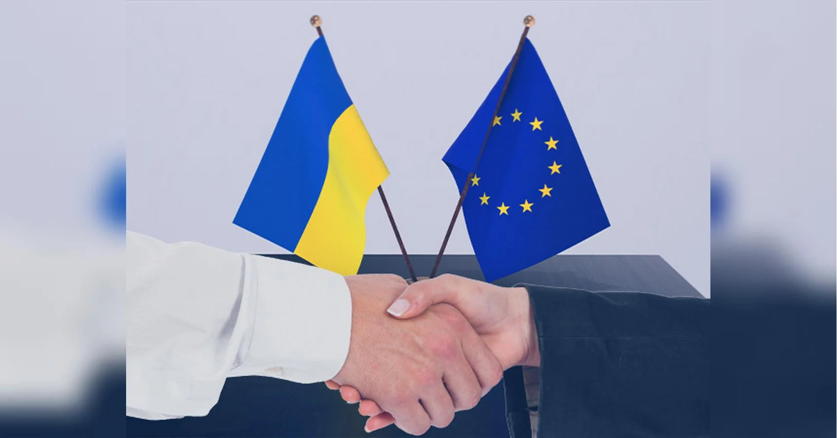 Рукостискання представників України та ЄС з прапорами двох сторін